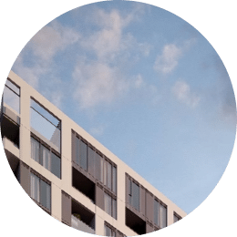 a closeup of a building with tall windows underneath a blue sky and fluffy clouds