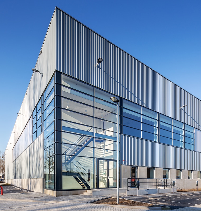A tall white industrial building with large glass windows
