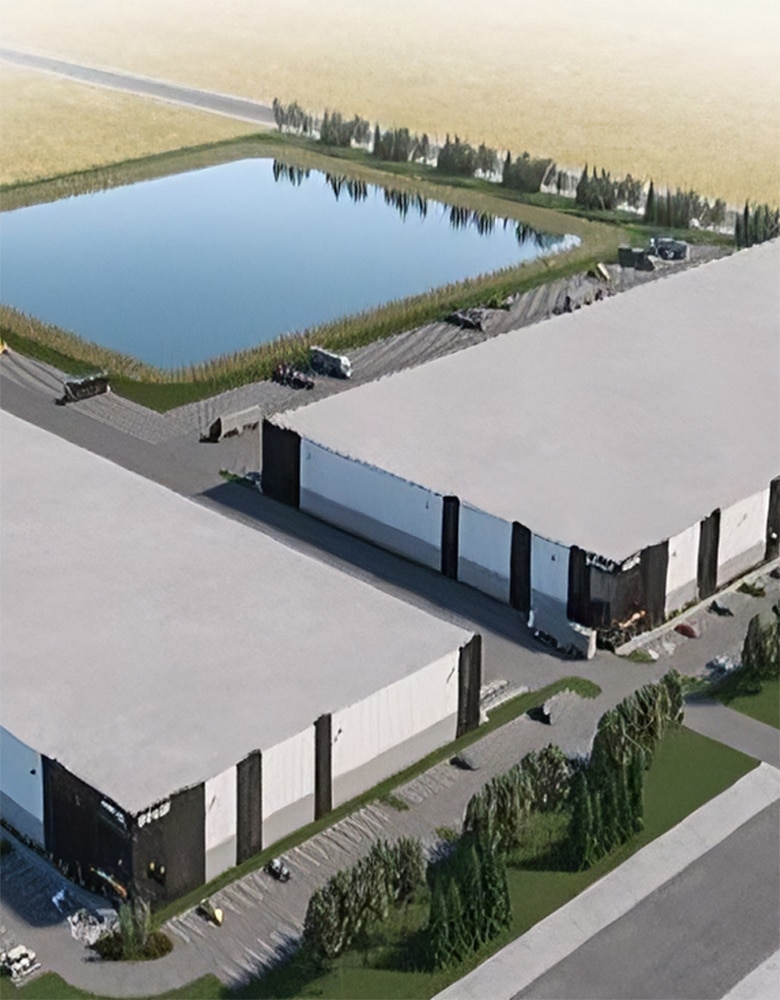 two industrial buildings sit peacefully next to a green field and a perfectly rectangle calm pond