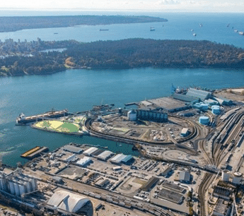 Bird’s-eye view of a developing industrial landscape with construction activity visible; expansive bodies of water stretch across the horizon, framing the site with natural contrast